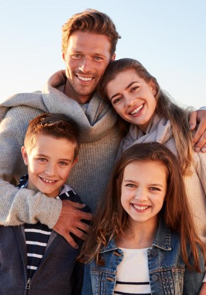 Famiglia sorridente sulla spiaggia al tramonto.