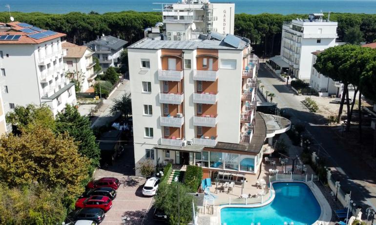 Hotel con piscina, vicino al mare, circondato da alberi e altre strutture.