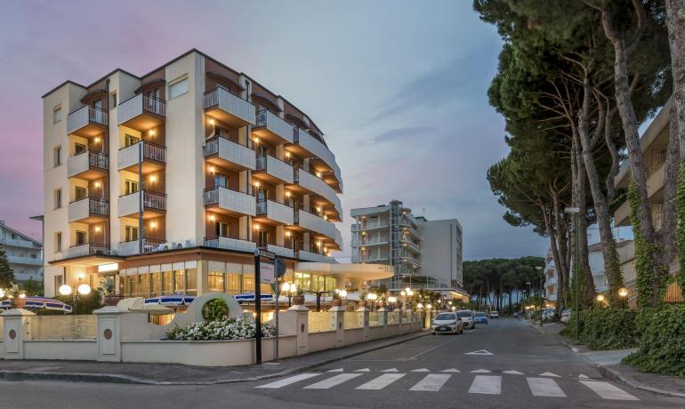 Hotel moderno al tramonto, vicino a una strada alberata.