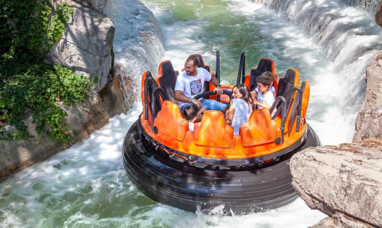 Famiglia si diverte su una giostra acquatica in un parco a tema.