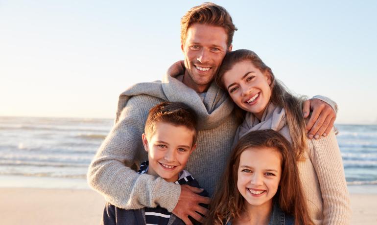 Famiglia sorridente sulla spiaggia al tramonto.