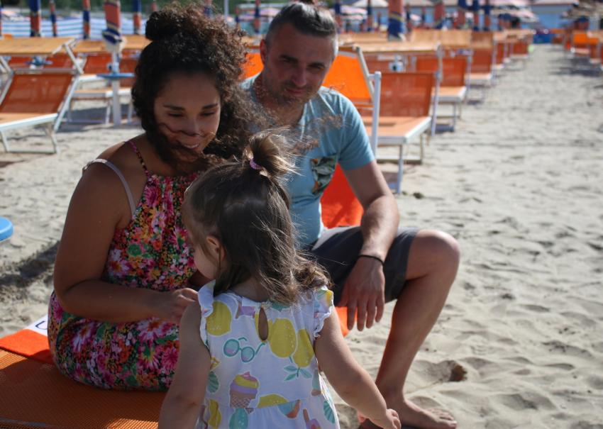 Famiglia sorridente in spiaggia, sole e gioia estiva.